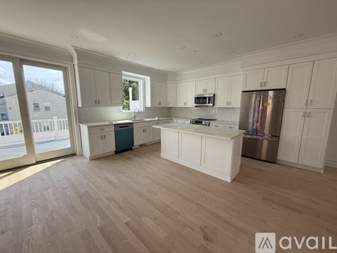 A spacious kitchen with white cabinets and a wooden floor.