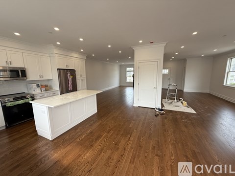 A kitchen with white cabinets and a wooden floor.