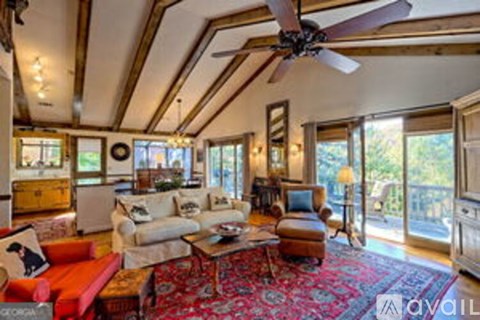 A living room with a red rug and a ceiling fan.