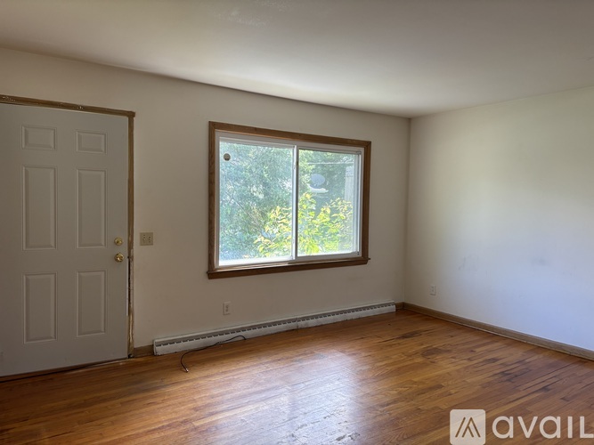 A room with a door and a window with a view of trees.