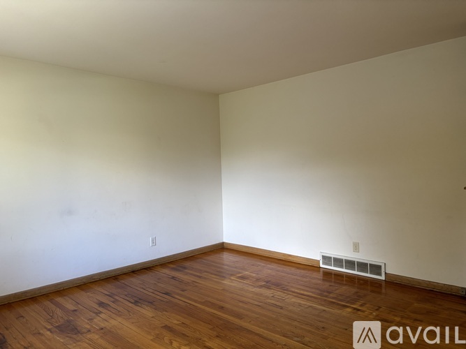 A room with wooden floors and a wall-mounted air conditioner unit.