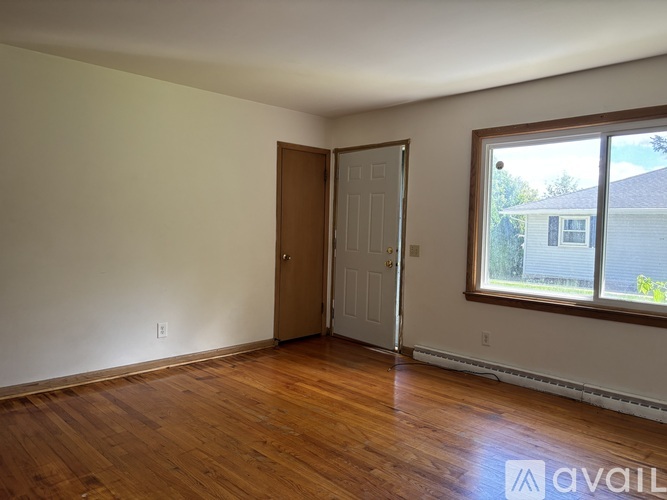 A room with wooden floors and a door leading to a balcony.