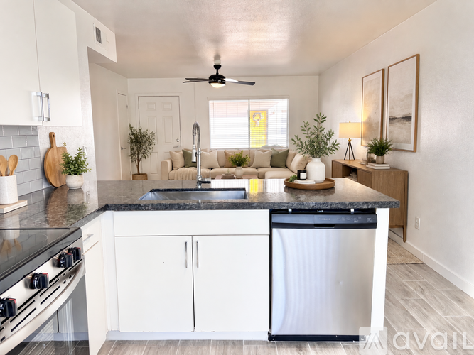 A kitchen with a stainless steel refrigerator, black countertops, and white cabinets.