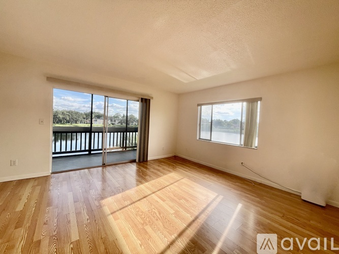 A room with wooden flooring and a sliding glass door leading to a balcony.