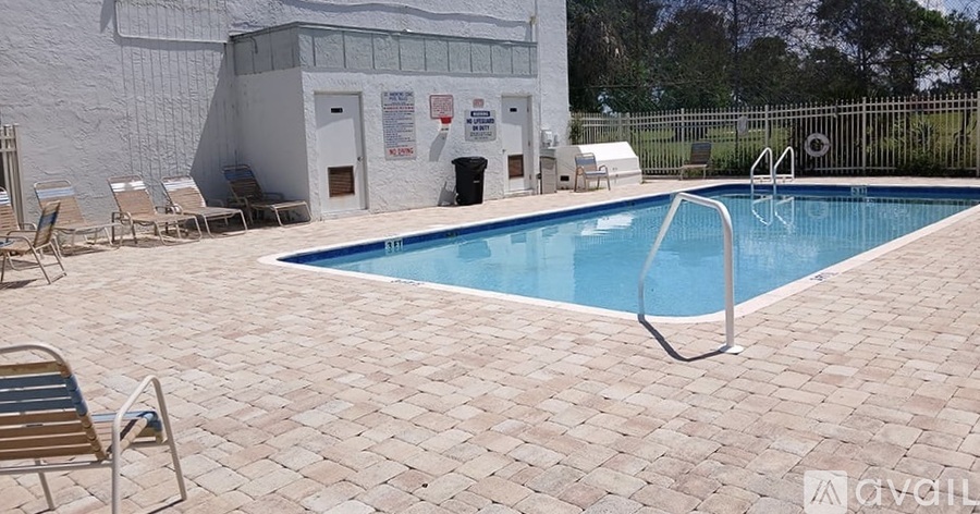 A pool with a diving board and a building in the background.