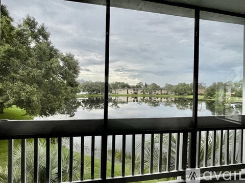 A balcony with a view of a lake and trees.