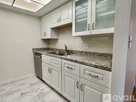 A kitchen with white cabinets and a granite countertop.