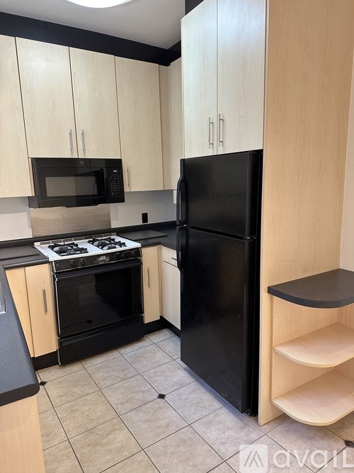A kitchen with black appliances and wooden cabinets.