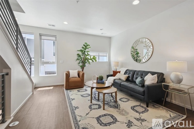 A living room with a black couch, a wooden table, and a rug with a geometric pattern.