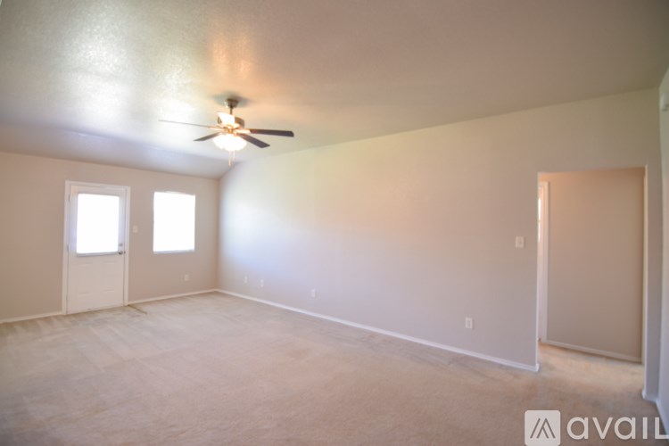 A room with a ceiling fan and two windows.