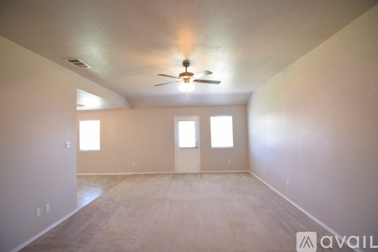 A spacious room with a ceiling fan and two windows.