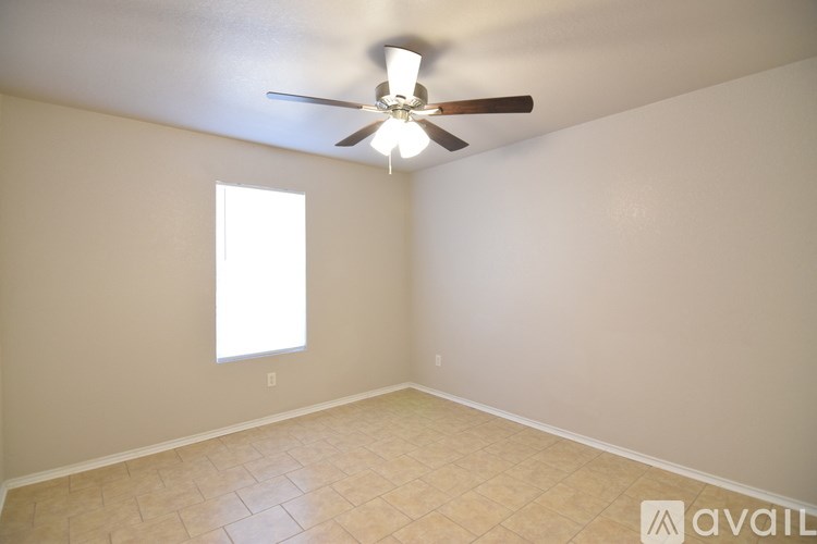 A spacious room with a ceiling fan and three windows.