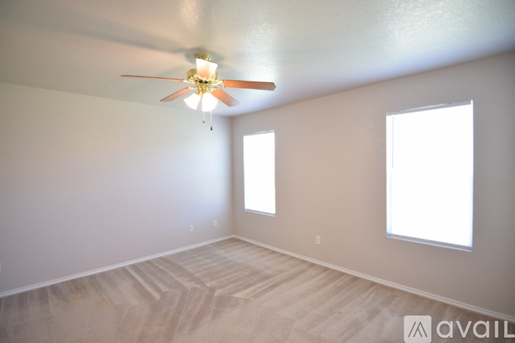 A room with a ceiling fan and two windows.
