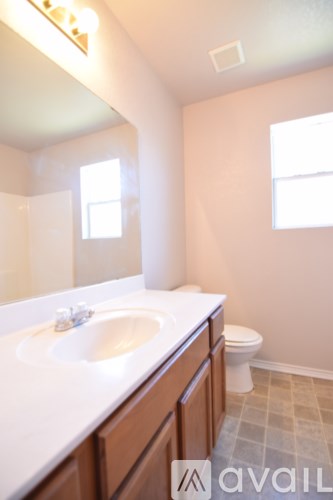 A bathroom with a toilet, sink, and mirror.