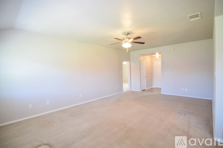 A room with a ceiling fan and light fixture, and a doorway leading to another room.