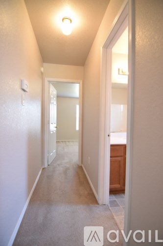 A hallway with a carpeted floor and white walls.