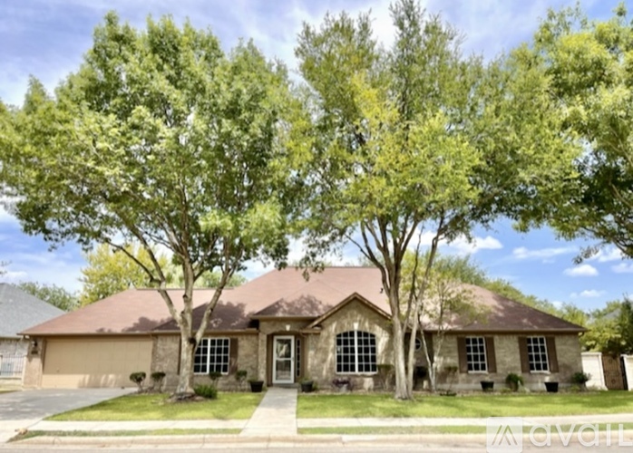 A house with a brown roof and a front yard with trees.