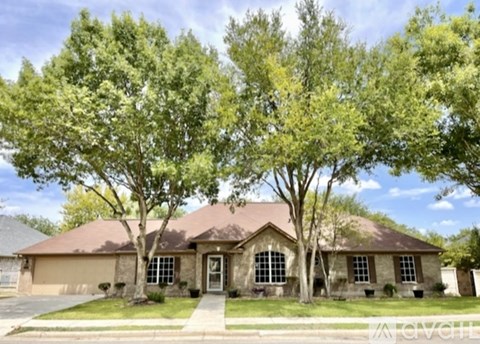 A house with a brown roof and a front yard with trees.
