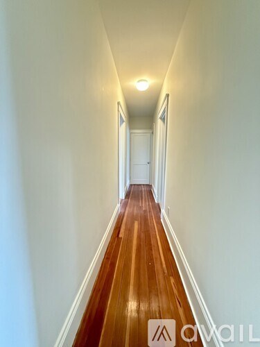 A long hallway with wood floors and white walls.