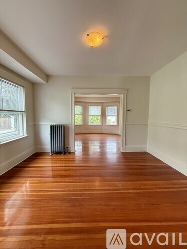 A room with wooden floors and a window on the left side.