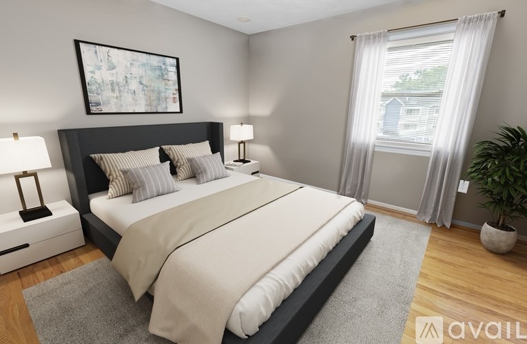 A bedroom with a large bed, two lamps, and a painting on the wall.