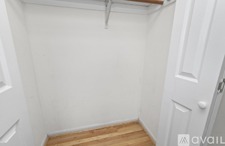A small white room with a wooden floor and a door on the right.