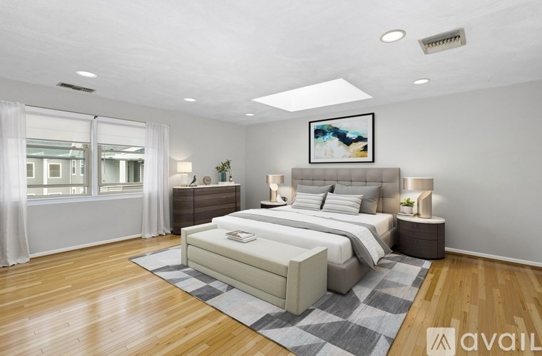 A bedroom with a large bed, a nightstand, and a painting on the wall.