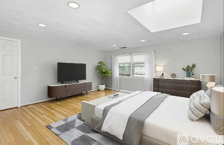 A bedroom with a bed, a television, and a window.