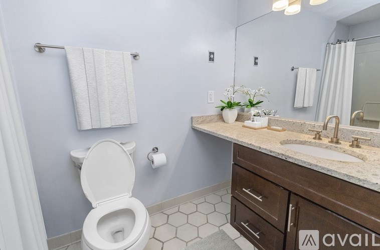 A bathroom with a toilet, sink, and mirror.