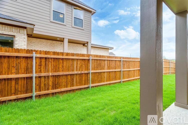 A house with a brown fence and green grass in front.