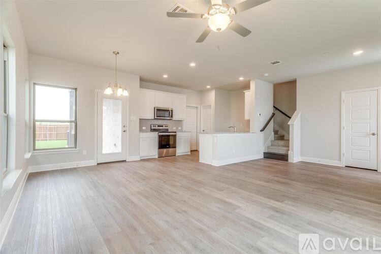 A spacious living room with a fan and lighting fixtures.