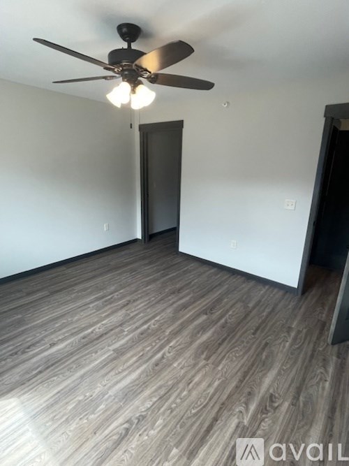 A room with a ceiling fan and wooden flooring.