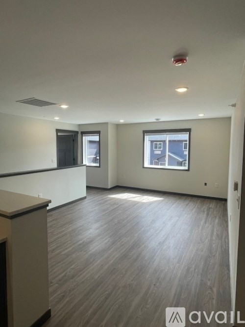 A spacious room with a window and a wooden floor.