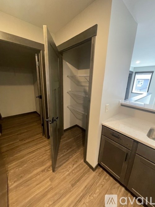 A kitchen with a wooden floor and a refrigerator with its door open.