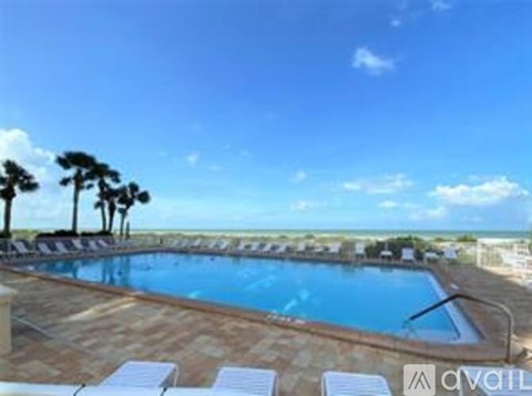 A pool surrounded by palm trees and deck chairs.