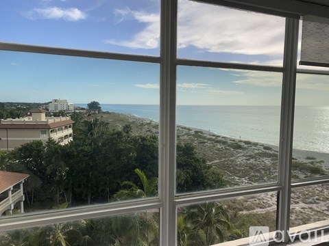 A view from a window looking out to a beach and buildings.