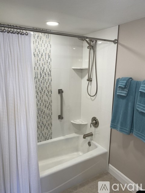 A white bathtub with a shower curtain and a towel hanging on the wall.