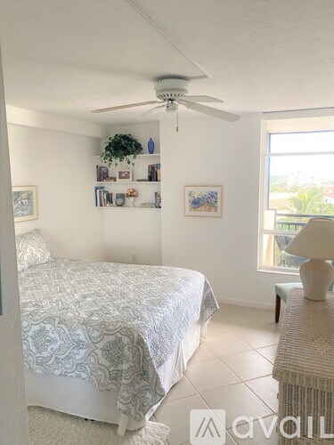 A bedroom with a bed, a ceiling fan, and a window.