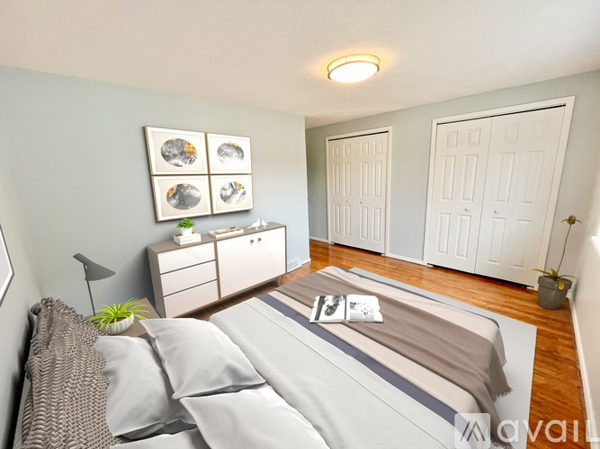 A bedroom with a bed, nightstand, and a plant.