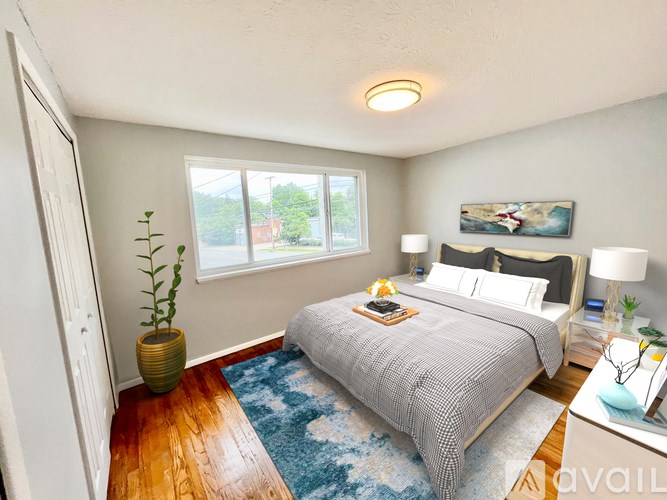 A bedroom with a bed, nightstand, and a plant.