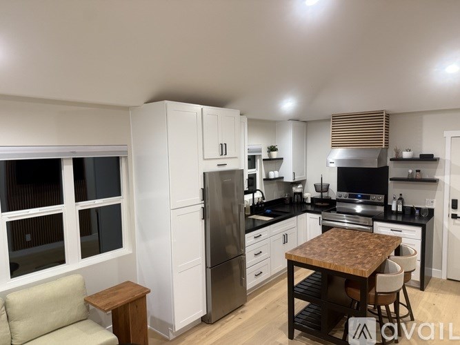A modern kitchen with wooden floors and white cabinets.