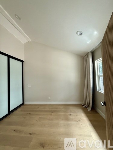 A room with wooden flooring and a window with curtains.
