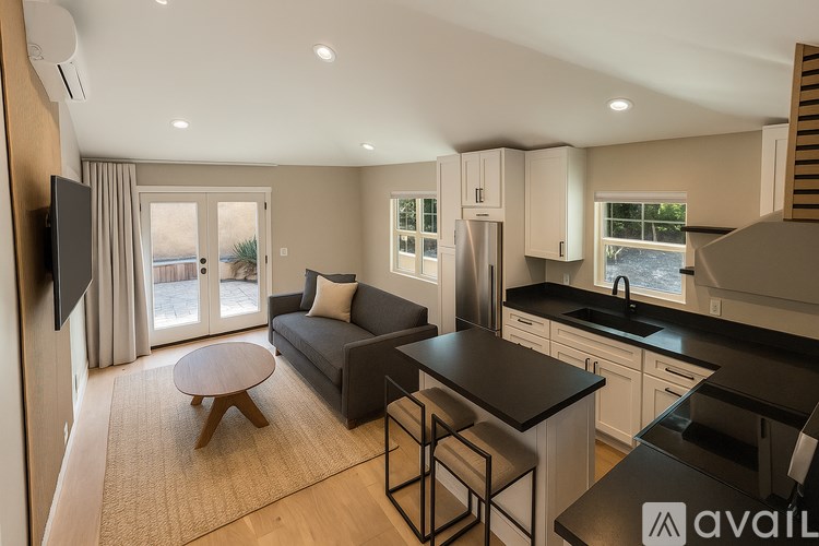 A modern kitchen and living room with a flat screen TV mounted on the wall.