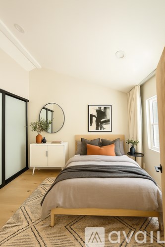 A bedroom with a bed, nightstand, and a mirror on the wall.