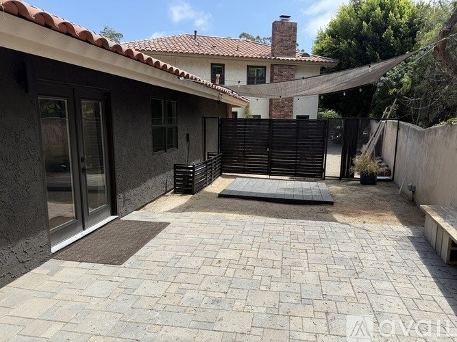 A patio area with a brick floor and a black gate.