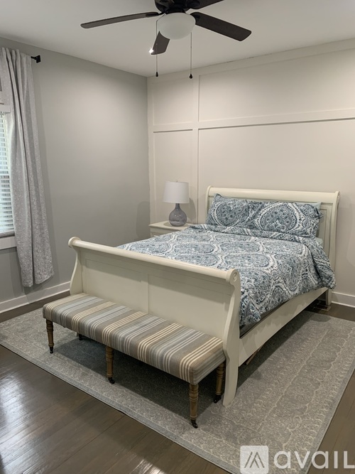 A bedroom with a bed, bench, and a ceiling fan.