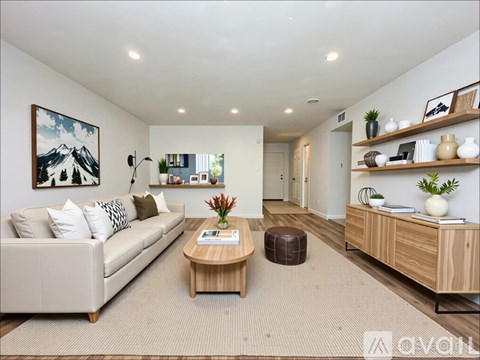 A living room with a white couch, a wooden coffee table, and a painting on the wall.
