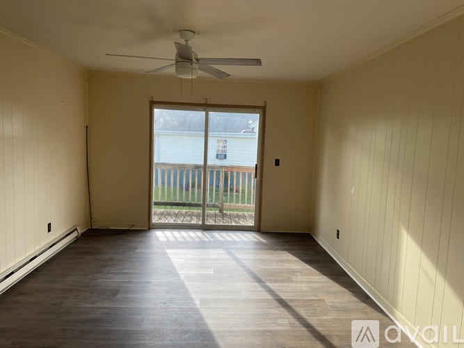 A room with a ceiling fan and sliding glass doors leading to a balcony.