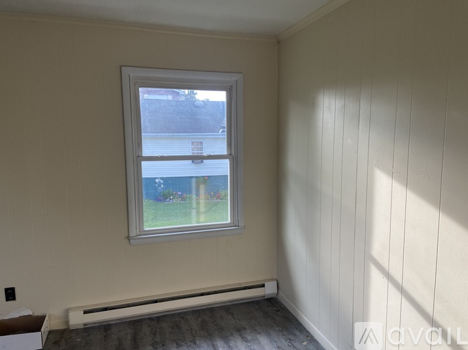 A room with a window and a radiator on the floor.