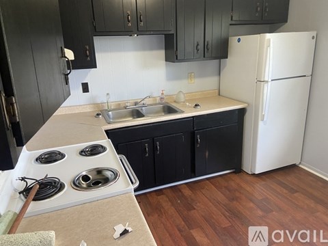 A kitchen with black cabinets and a white refrigerator.